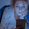 Woman looking at her cell phone in bed